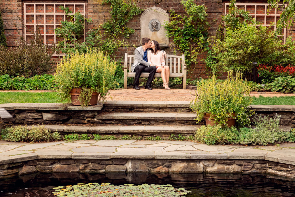 An engagement session for an engaged couple kissing in English garden at Chicago Botanic Garden in the summer by a wedding photographer Mila Craila Photography