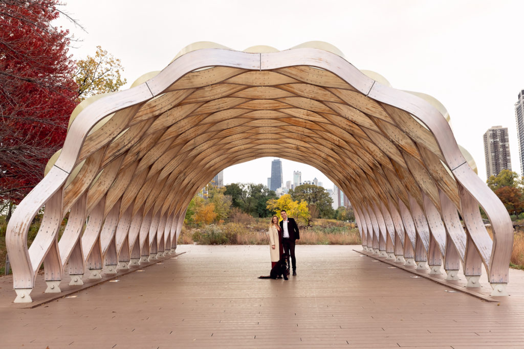 An engagement session for an engaged couple with a black dog in Lincoln Park in the fall by a wedding photographer Mila Craila Photography