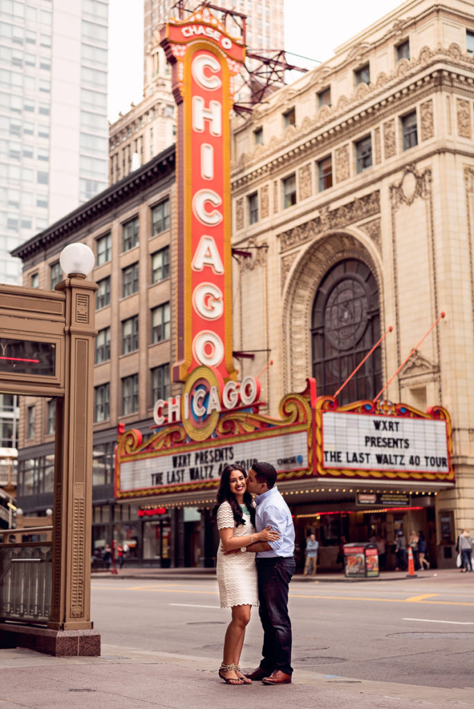 An engagement session for an engaged couple at the Chicago Theater sign in the summer by a wedding photographer Mila Craila Photography