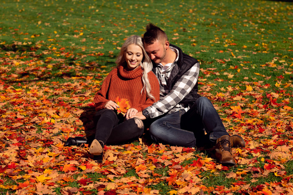 An engagement session for an engaged couple sitting on the ground at Cantigny Park in Wheaton in the fall by a wedding photographer Mila Craila Photography