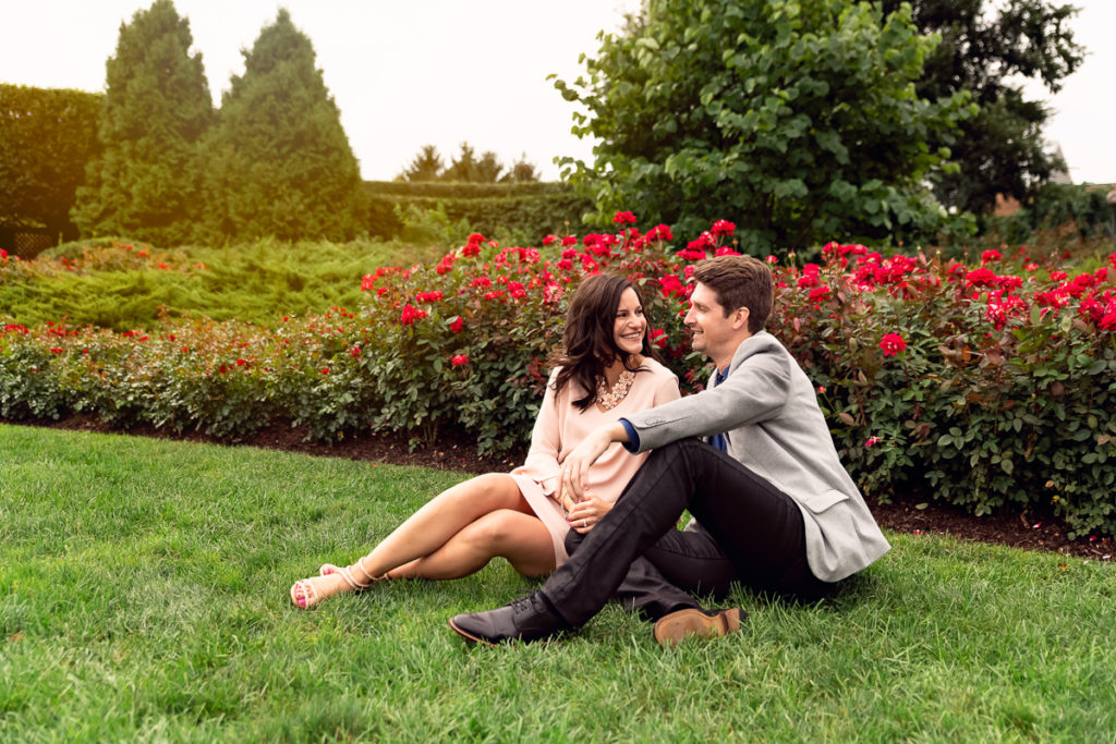 An engagement session for an engaged couple sitting in the rose garden at Chicago Botanic Garden in the summer by a wedding photographer Mila Craila Photography