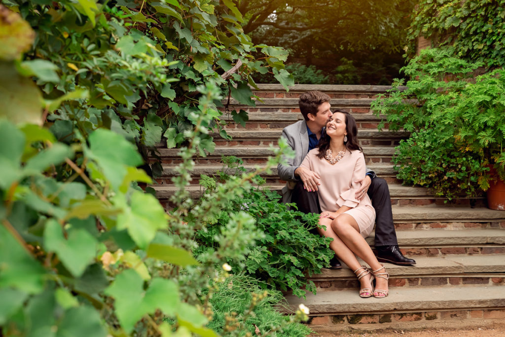 An engagement session for an engaged couple sitting on the stairs at Chicago Botanic Garden in the summer by a wedding photographer Mila Craila Photography