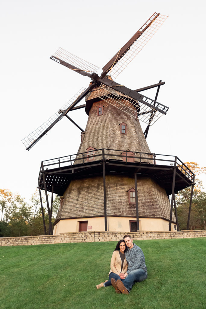 An engagement session for an engaged couple sitting near the windmill at Fabyan Forest Preserve in the fall by a wedding photographer Mila Craila Photography