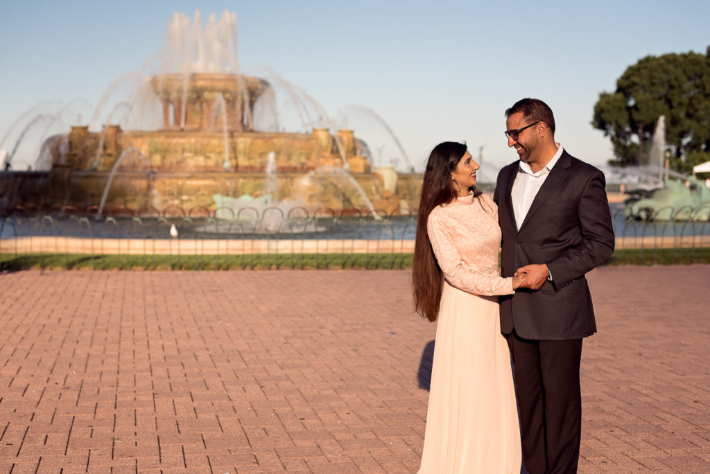 An engagement session for an engaged couple at the Buckingham Fountain in Chicago in the summer by a wedding photographer Mila Craila Photography