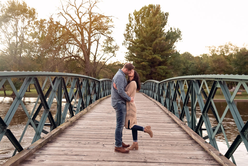 An engagement session for an engaged couple kissing on a bridge at Fabyan Forest Preserve in the fall by a wedding photographer Mila Craila Photography