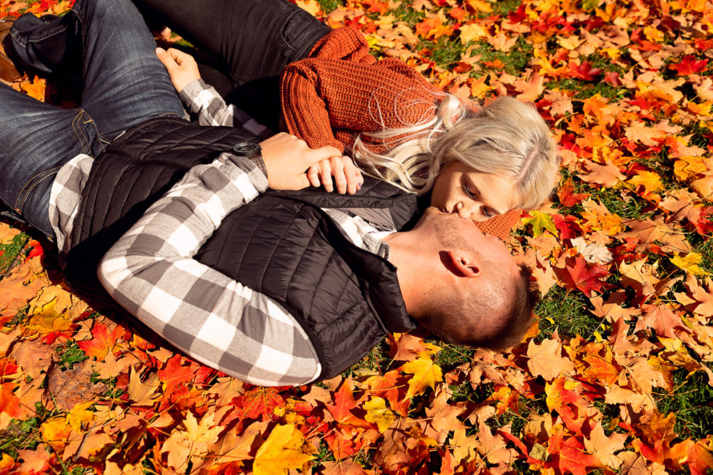 An engagement session for an engaged couple kissing on the ground at Cantigny Park in Wheaton in the fall by a wedding photographer Mila Craila Photography