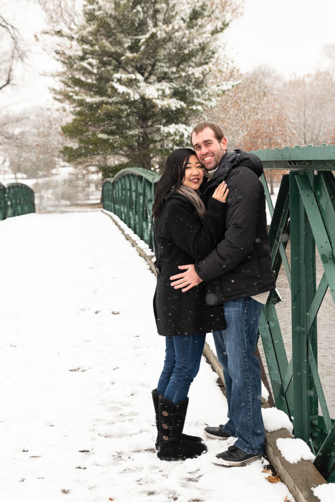 An engagement session for an engaged couple standing on a bridge at Fabyan Forest Preserve in the winter by a wedding photographer Mila Craila Photography