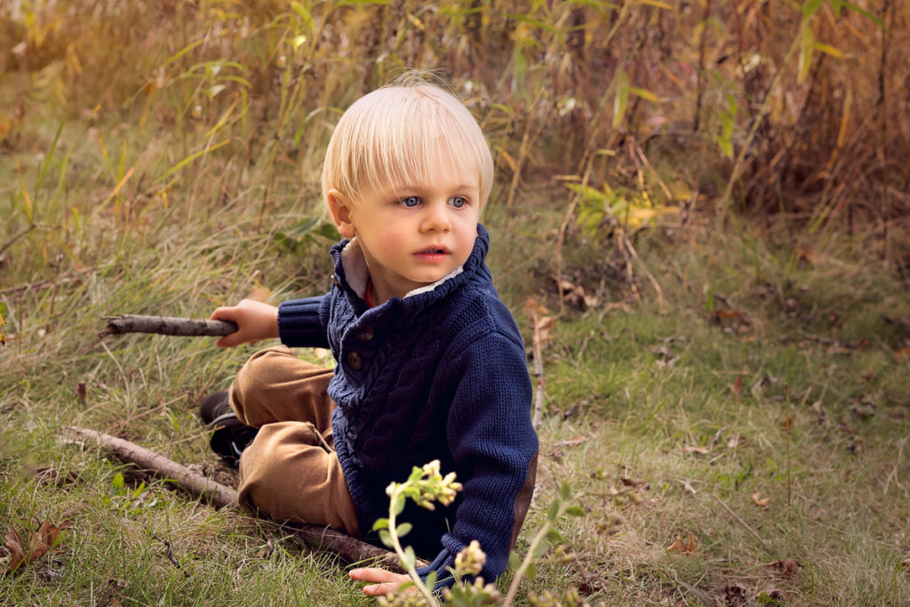 Family session for a little boy holding a wooden stick at Lincoln Park Zoo in Chicago in the fall by family photographer Mila Craila Photography