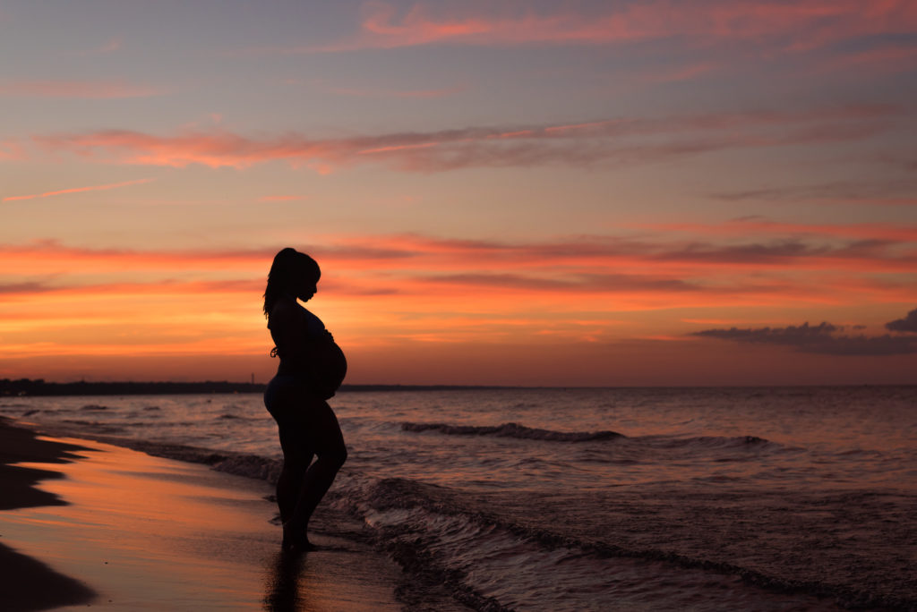 a pregnant woman on the beach at sunset