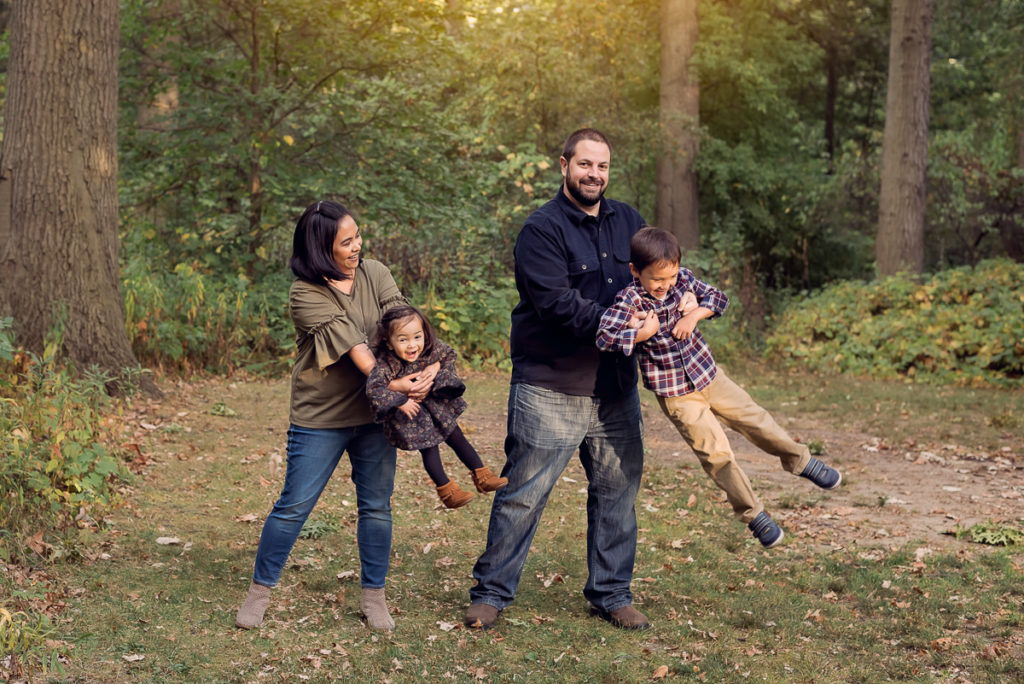 Family session for parents swinging kids at Emily Oaks Nature Center in Skokie by family photographer Mila Craila Photography