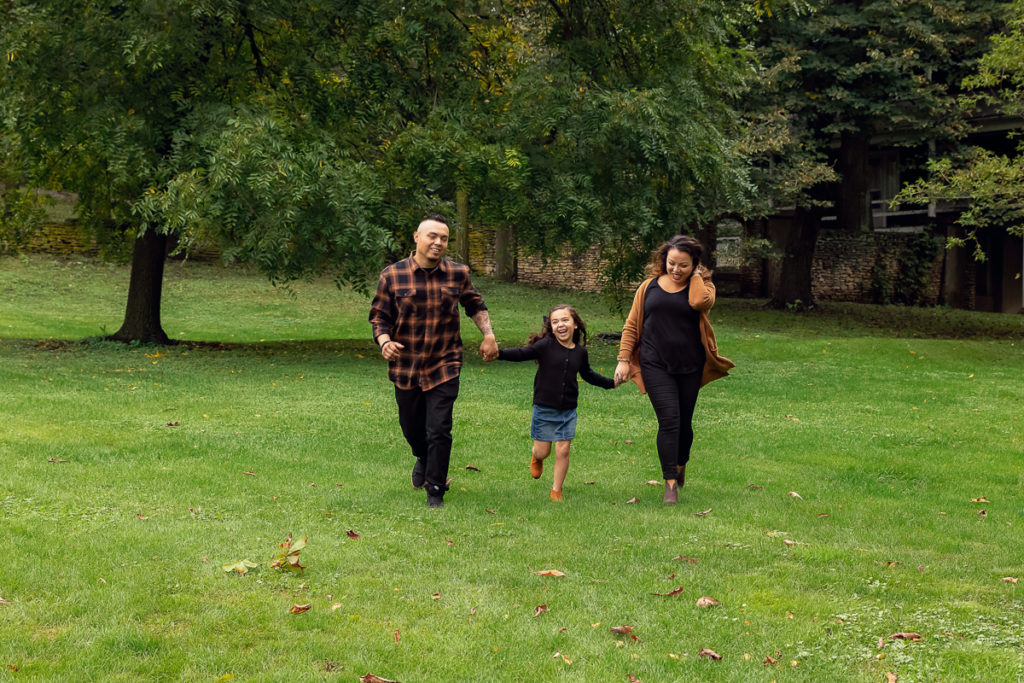 Family session for parents and a young daughter running at Fabyan Forest Preserve in Geneva by family photographer Mila Craila Photography