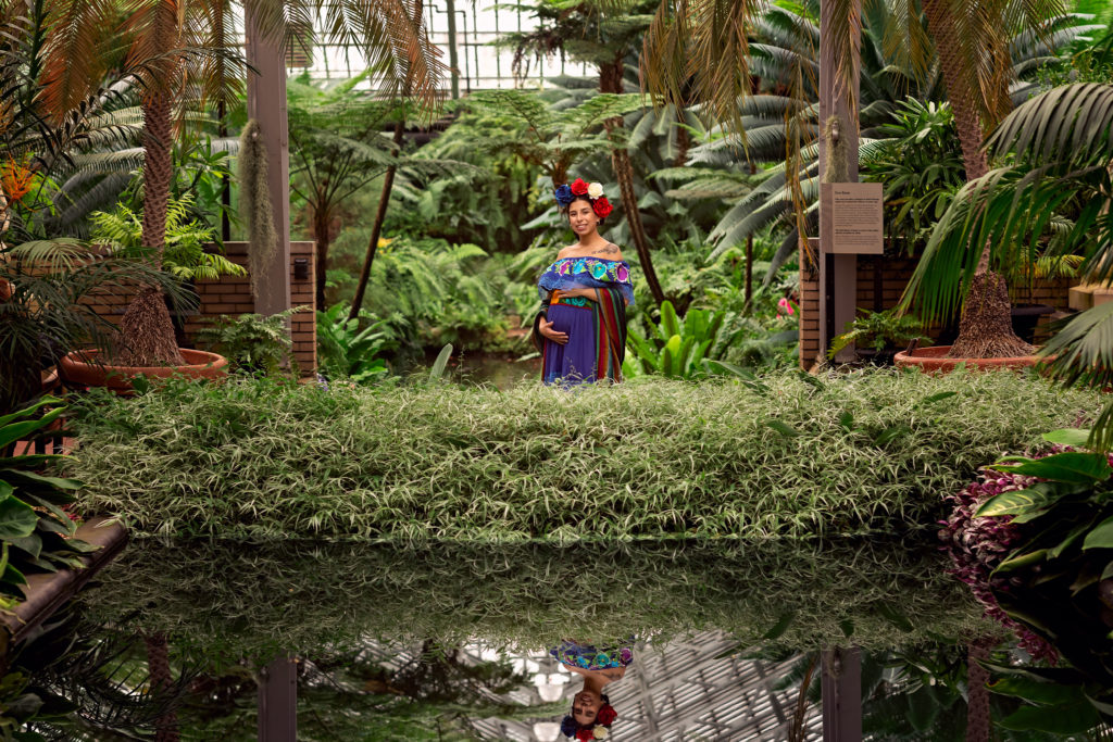 A maternity session for a pregnant woman in a traditional Mexican dress in Garfield Park Conservatory by a maternity photographer Mila Craila Photography