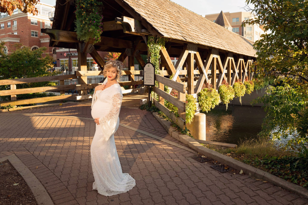 A maternity session for a pregnant woman in a white dress near the bridge on Naperville Riverwalk by a maternity photographer Mila Craila Photography