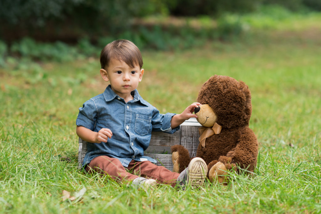 Toddler boy with a stuffed brown bear in a park by family photographer Mila Craila Photography